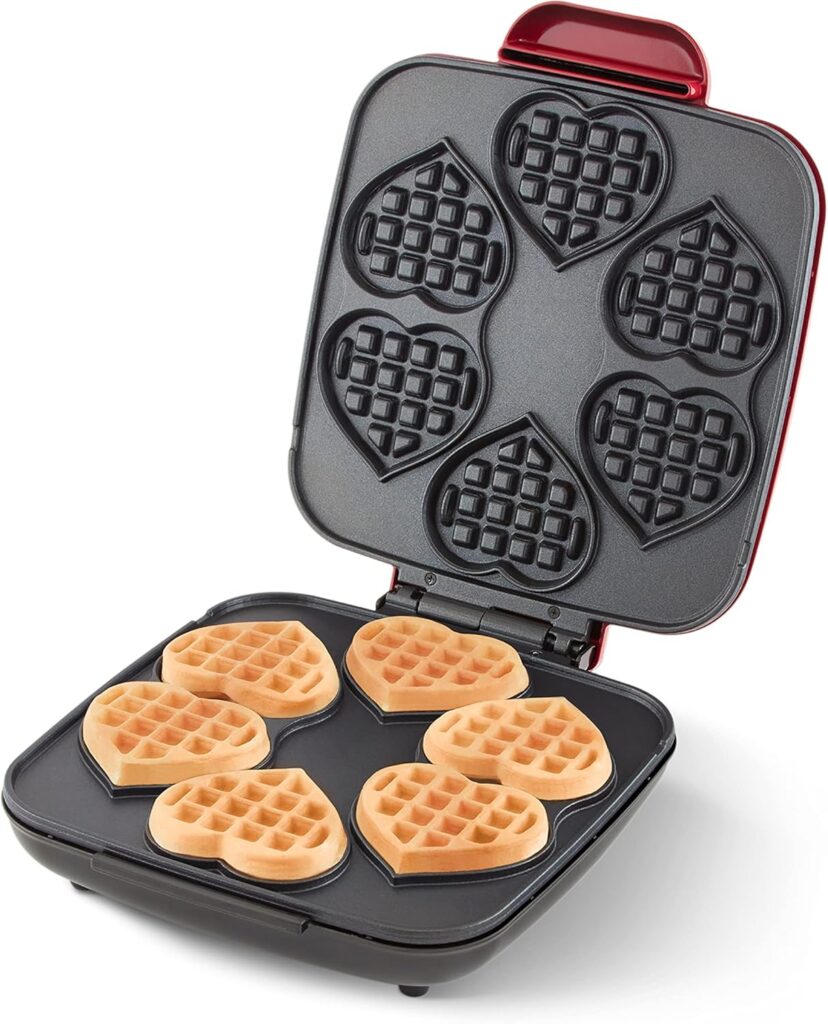 Waffle iron with six mini heart-shaped waffles inside, golden brown and freshly cooked.