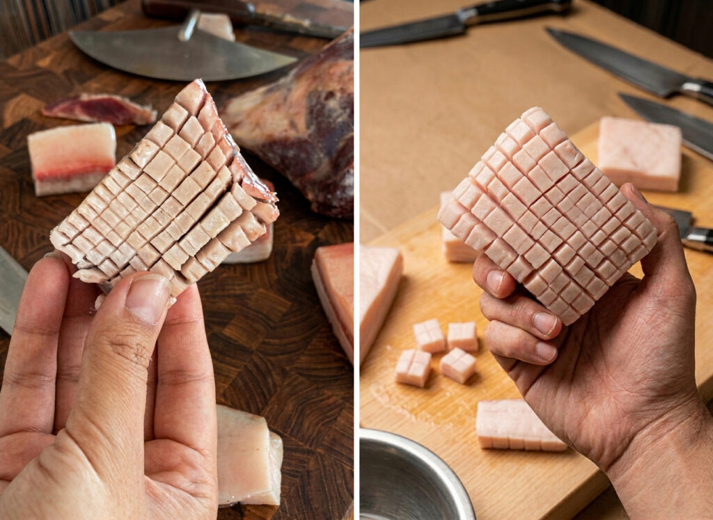 Hand holding a piece of imitation muktuk above a cutting board, showing layers of pork fat and dark skin designed to mimic traditional narwhal muktuk.