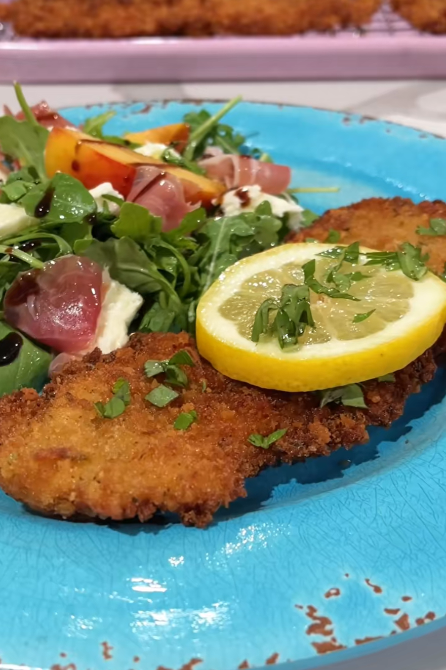 Golden brown lemon basil chicken cutlets garnished with fresh basil and lemon slices.